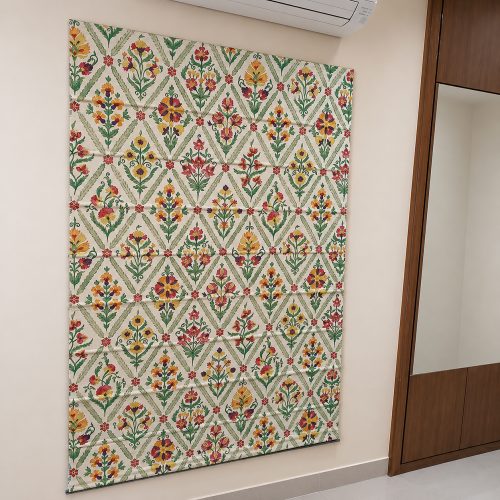 Jaipur-print roman blind with orange and green floral trellis pattern on a bedroom wall
