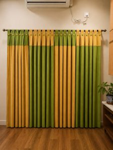 Window Coverings Kolkata: Blinds & Curtains Green and mustard pleated curtains with brass rings below a wall AC unit