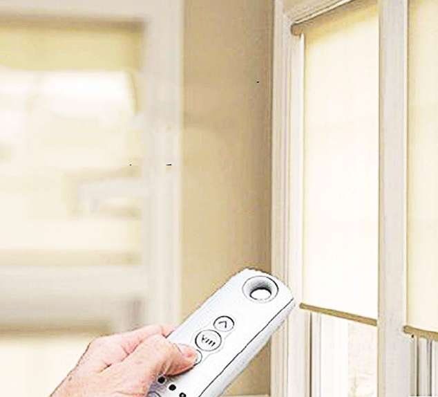 Hand using a remote control to operate motorised roller blinds